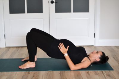 woman dressed in black doing a bridge pose while pregnant